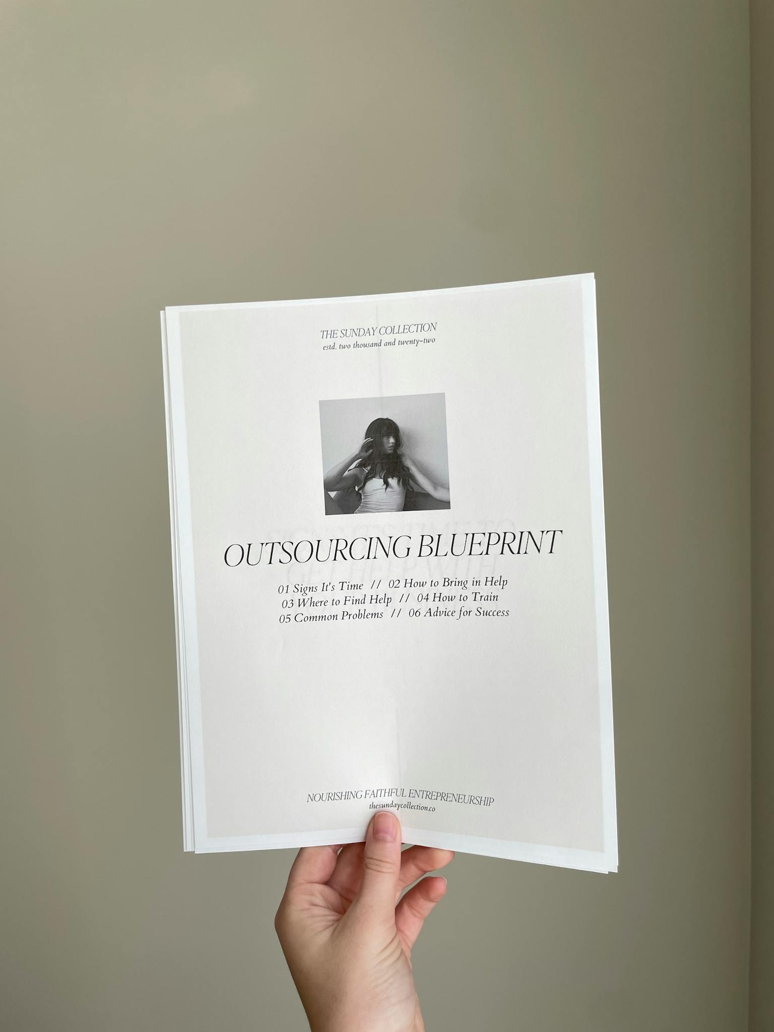 Close-up of a hand holding a business document titled 'Outsourcing Blueprint'.